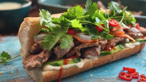 GMVozd/Getty Images A bánh mì, covered in coriander and served alongside slices of chilli, is shown on a table
