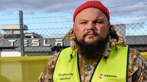 Striking Tesla mechanic Janis Kuzma standing on the picket line outside a Tesla garage in Malmö