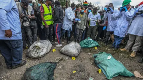 Getty Images Investigators take pictures of body bags retrieved from a Nairobi rubbish dump