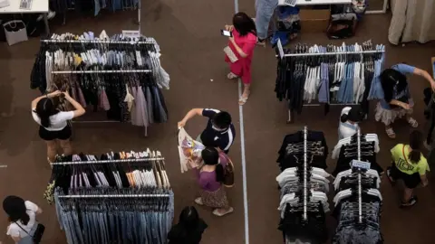 Getty Images People shop for clothes at a mall in Shenzhen, in China's southern Guangdong province on May 21, 2020.