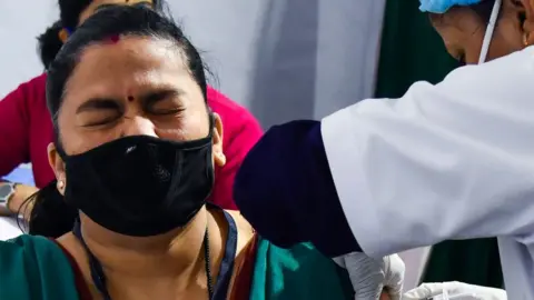 Getty Images A medical worker inoculates a colleague with a Covid-19 vaccine at a hospital in Guwahati on January 16, 2021