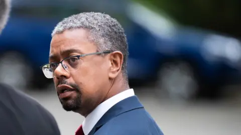 PA Media Vaughan Gething walking while looking over his shoulder