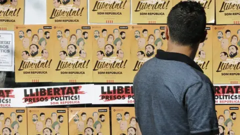 EPA A man looks at posters during a demonstration to protest against the imprisonment of eight former members of Catalan government