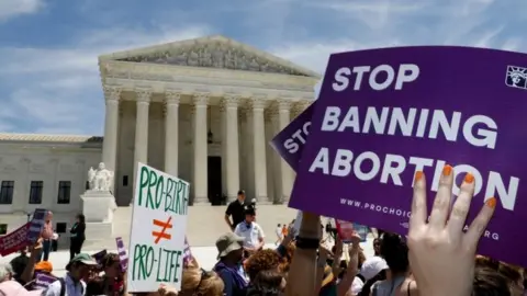 Reuters A protester outside the Supreme Court in Washington DC holds a sign reading, "Stop banning abortion"