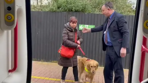 Sarah Leadbetter being helped onto the train by a guard