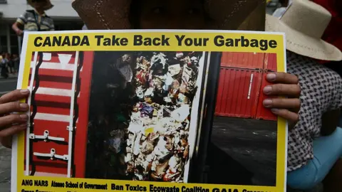 Getty Images A protesters holding a poster of the shipping container in the port of Manila.