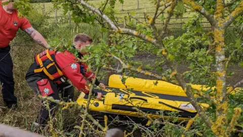 RSCPA Two firefighters push a yellow raft out on to the muddy pond