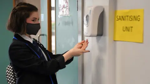 Getty Images Girl sanitises hands at school