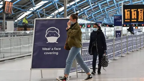 Getty Images A sign tells passengers to "wear a face covering" at Waterloo train station in central London