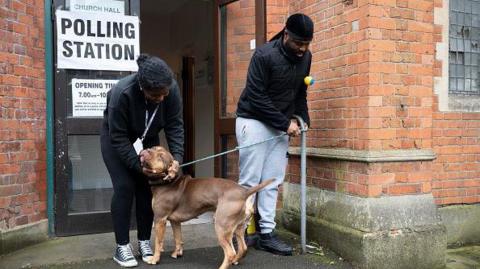 Man and woman with dog at polling station