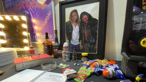 Table in the replica of Lemmy's dressing room including his glasses, cigarettes, candy and chocolate