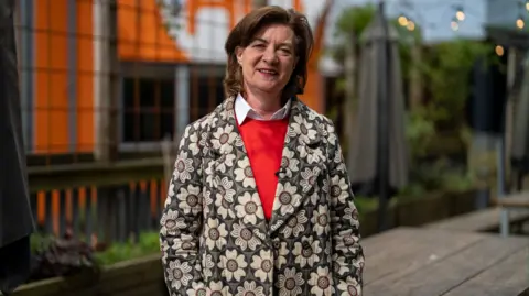 Eluned Morgan in a flowery blazer and red jumper
