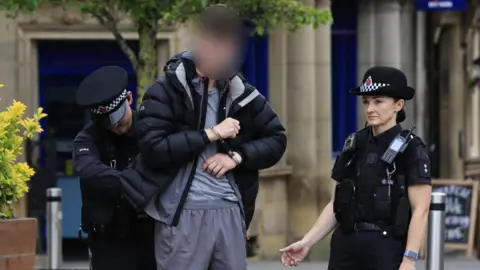 GMP Young male being arrested by two police officers. His face is blurred.