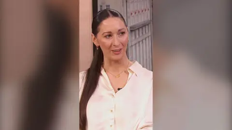 The Traitors UK joint winner Rachel Duffy. She has long brown hair and wears a white shirt.