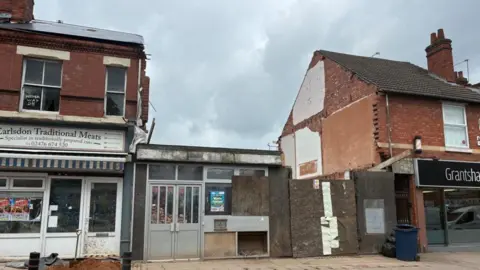 A partially demolished building in between two shops
