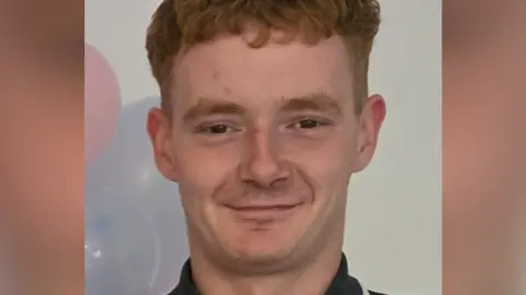 Family photo of Cain Parker wearing a polo shirt with balloons behind him
