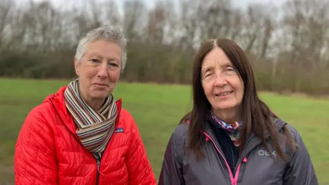 Liz Pritchett, left, standing next to Diane Maloney standing in the park with trees visible behind
