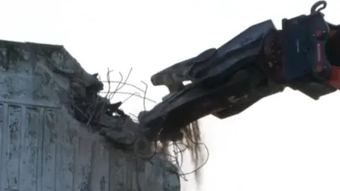 A multi-storey car park is the first major building to be cleared, with hydraulic crushing machines.