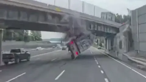A tractor trailer is flipped over after hitting the overpass.