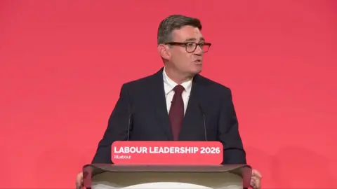 Andy Burnham in a suit giving a speech