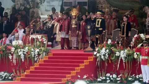 EPA Indonesian President Joko Widodo salutes on a stage decorated by a red carpet and flowers. 