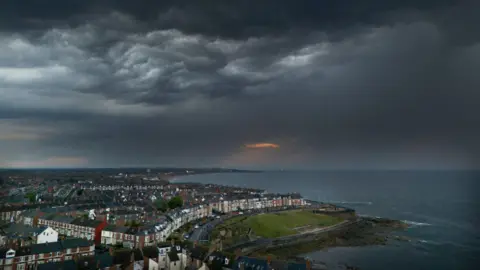 A landscape image of  Whitley Bay in North Tyneside along the coastline. Dark clouds have gathered across the sky.