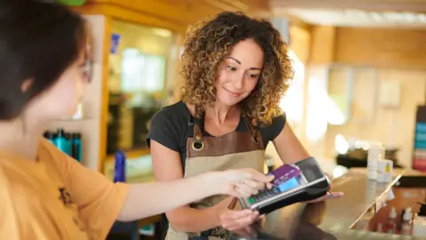 Getty Images A woman receives a card payment from a customer in a salon