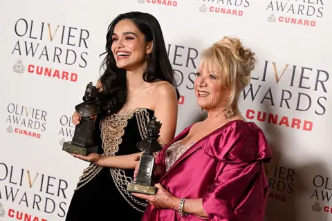 Getty Images Rachel Zegler in a black and gold stands beside Elaine Page in pink