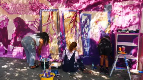 London School of Muralism Two people work on a mural, which was a collaboration between The London School of Muralism and traders from Deptford's second-hand market.