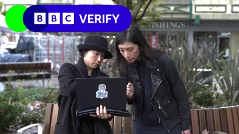 BBC Two women standing outside looking intently at a laptop