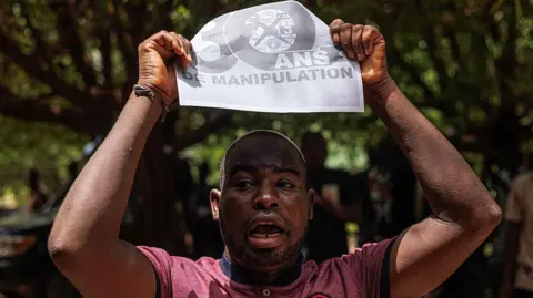 A demonstrator holds a banner written manipulation in Bamako 