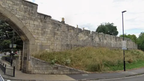 Google A grass verge runs alongside historical city walls in York.