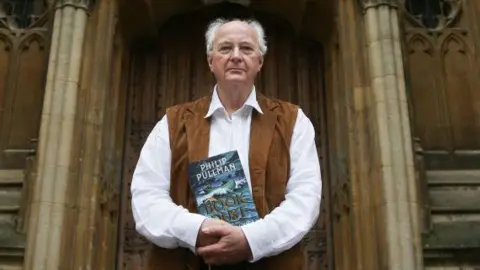 Getty Images Pullman stands outside the Bodleian Libraries in Oxford holding a copy of the first of his Book of Dust trilogy, La Belle Sauvage.