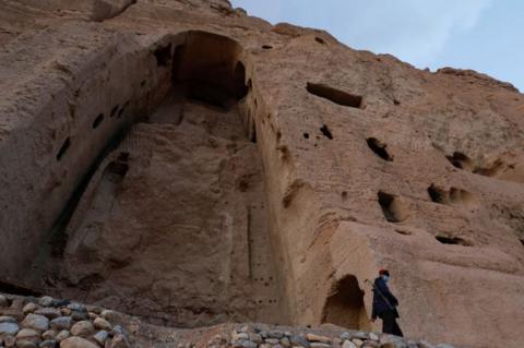 A file photo from March 2024 of a Taliban soldier standing guard in front of the ruins of a 1,500-year-old Buddha statue in Bamyan