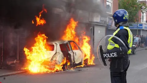 PA Media A car burns on Parliament Road in Middlesbrough during an anti-immigration protest.