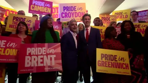 A group of Labour politicians holding up signs that say Pride In and the names of various London boroughs.