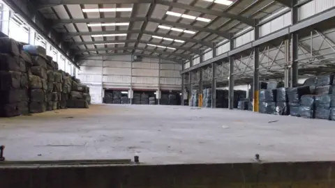 Environment Agency Large stacks of bales of rubbish piled high in a warehouse. 
