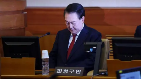 EPA South Korean Yoon Suk Yeol looks down while sitting in the dock in the courtroom