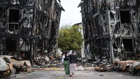 People look at burned-down buildings after a magnitude 7.2 earthquake struck Venezuela and other regions in the Caribbean on June 30, 2026 in Caracas, Venezuela.