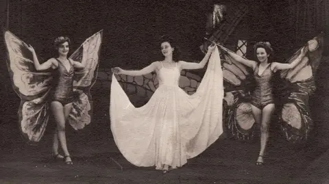 An Iodhlann Women on stage with two dressed with butterfly wings and a woman in a white dress