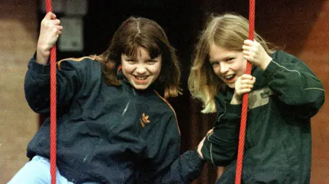 PA Media Jessica Chapman (left) and Holly Wells smiling playing on swings