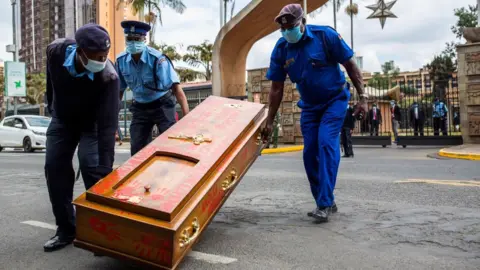 Getty Images Kenyan police officers remove an empty coffin left after the protest against police brutality in Nairobi on June 9, 2020.