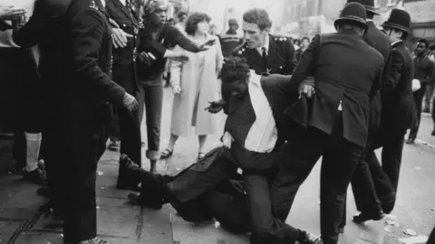 Getty Images A black man is arrested by two white police officers in Brixton