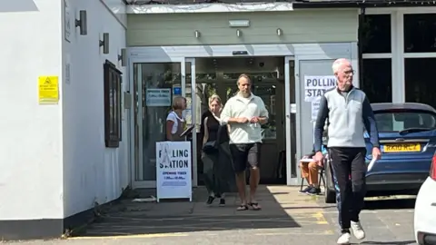 Julia Gregory/BBC Voters leaving Claygate village hall polling station on Thursday morning