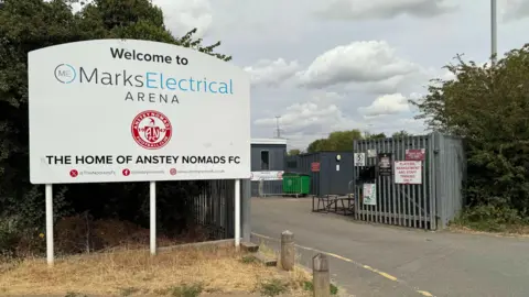 Un semn alb în fața clubului de fotbal pe care scria „Bun venit la Marks Electrical Arena”.