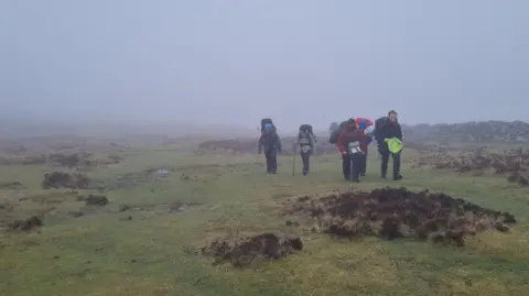 Plymouth College A group of teenagers walking on the moor on a wet and rainy day. 