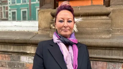 Charlotte Charles wearing a pink scarf outside the coroner's court brick building