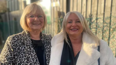 BBC Rebecca Stewart (r) with her mum Coral Jeffery, standing outside, wearing coats. 