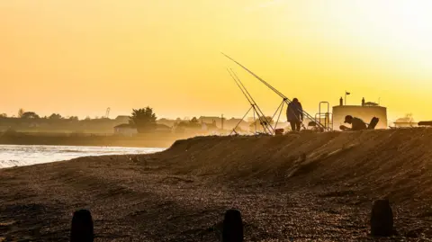 Anna Sukeforth Fishers with their lines during a sunrise on the coast. 
