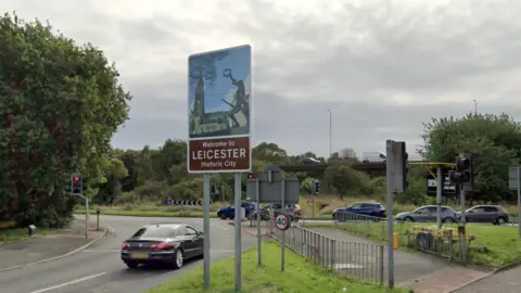 A sign saying "Welcome to Leicester - Historic City, next to a traffic island